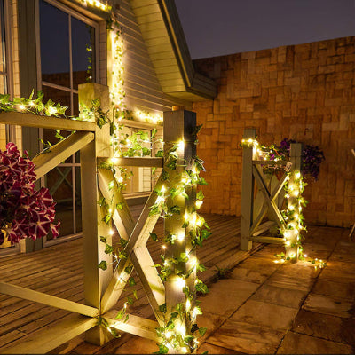 Guirlande solaire extérieur en lierre artificiel avec LED blanc chaud, sur terrasse en bois, ambiance chaleureuse.