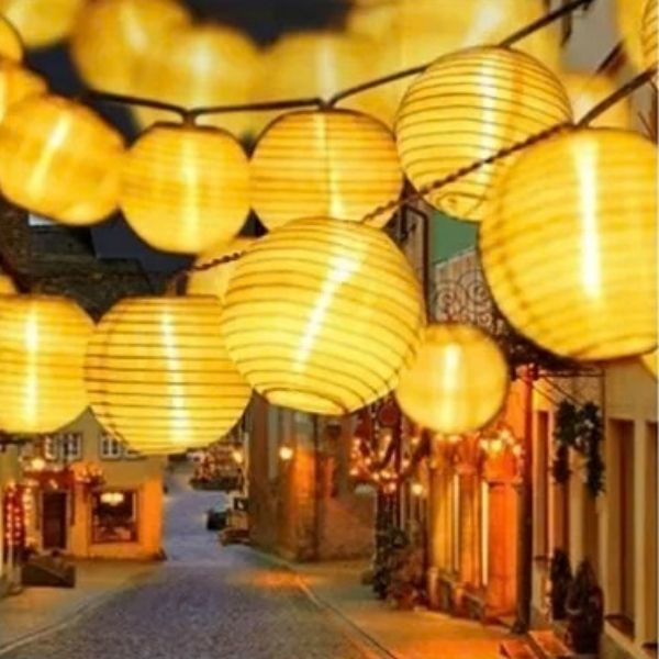 Guirlande solaire LED blanc chaud suspendue dans rue de village pour eclairage exterieur chaleureux et decoratif