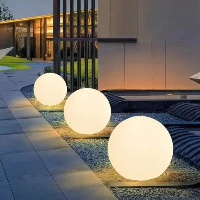 Lampe solaire extérieur boule blanc chaud alignée dans allée et maison éclairée en arrière-plan