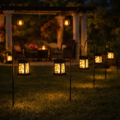 lanterne solaire accrochée à des piquets avec tonnelle en fond et salon de jardin