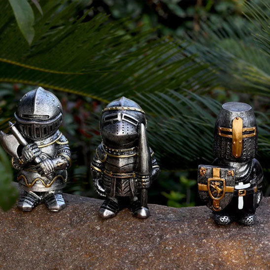 Statue de jardin trois chevaliers décoratifs posés sur une pierre devant des plantes