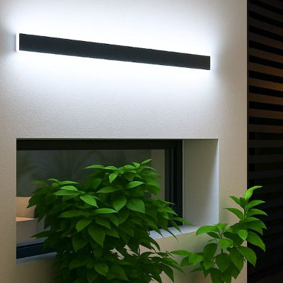 Applique exterieur noir avec lumière blanche fixée au-dessus d'une fenêtre horizontale avec des plantes en dessous