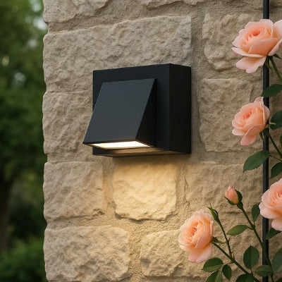 applique murale exterieure fixée sur un mur en pierre de taille illumine, à droite des roses