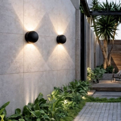 applique murale exterieure noire sur mur extérieur beige avec plantes vertes et arbre