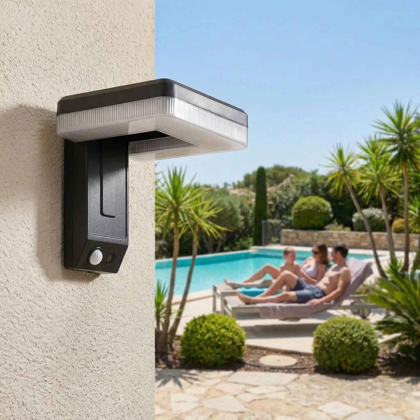 appliques exterieures solaires sur mur en plein soleil avec famille sur chaises longues au bord de la piscine dans jardin paysager