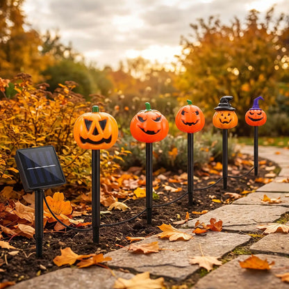 Décoration citrouille Halloween solaire installée le long d'une allée en pierre, en plein jour à l'automne