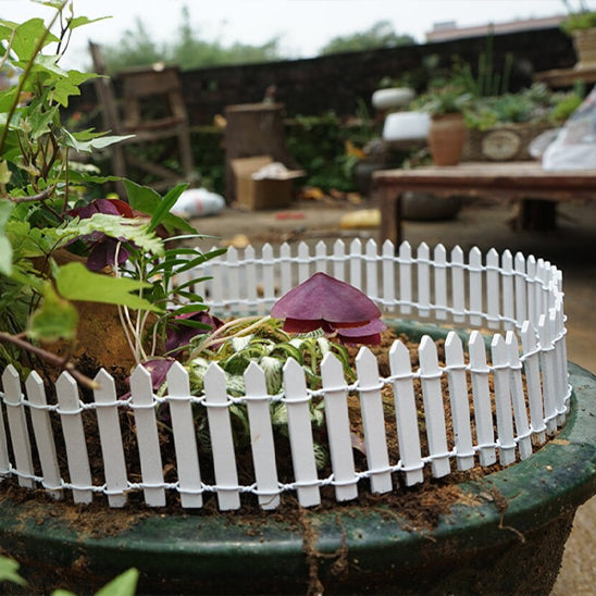 Décoration extérieur jardin moderne clôture blanche miniature entourant un petit jardin fleuri