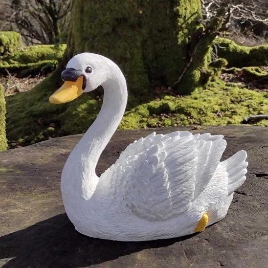 Décoration extérieur jardin moderne cygne blanc posé sur une souche en bois devant des arbres