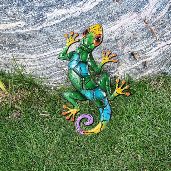 Lézard décoratif mural vert et bleu en métal appuyé contre une pierre, deco jardin extérieure
