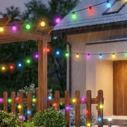 Guirlande boule lumineuse multicolore suspendue résistante à la pluie installée sur pergola et clôture dans un jardin extérieur