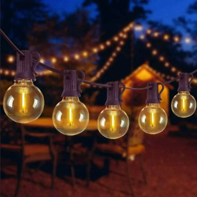 guirlande guinguette solaire suspendue sur terrasse avec chalet éclairé en arrière-plan.