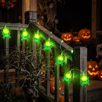 Guirlande halloween à araignées LED vertes sur la rampe en bois d'un escalier extérieur, citrouilles sculptées éclairées en arrière-plan