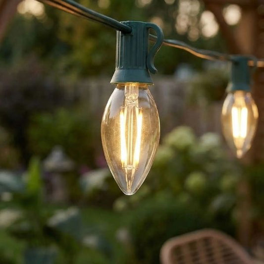 Guirlande lumineuse extérieur ampoule C7 LED blanc chaud en verre installée dans jardin pour terrasse chaleureuse