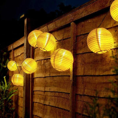 guirlande solaire extérieure lumière chaude accrochées sur clôture en bois.