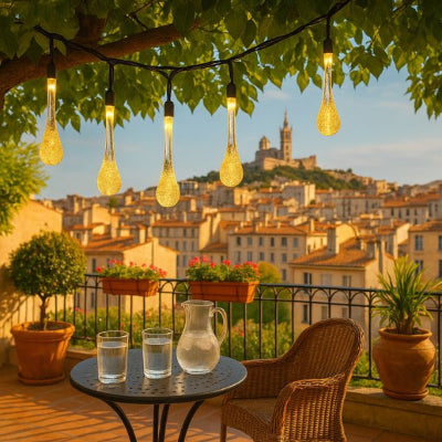 guirlandes solaires extérieures en forme de gouttes lumineuses suspendues sur terrasse avec vue sur toits et basilique au coucher du soleil