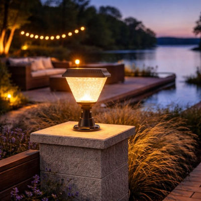 lampe exterieur solaire sur pilier en bord de lac avec guirlande lumineuse et salon de jardin à la tombée de la nuit
