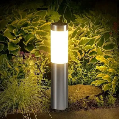 Lampe solaire extérieur LED inox éclairant un massif de jardin.
