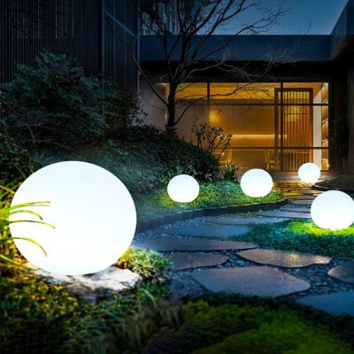 Allée de jardin illuminée par lampe solaire extérieur en forme de boule et maison éclairée au fond