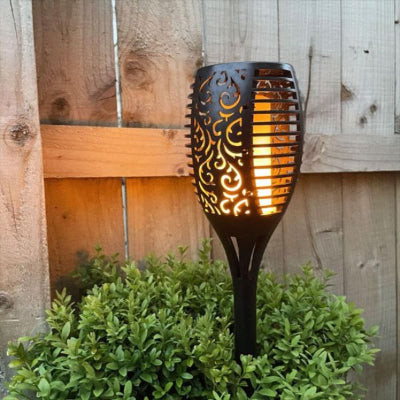 Lampe solaire extérieur à effet flamme installée devant un mur en bois dans le jardin.
