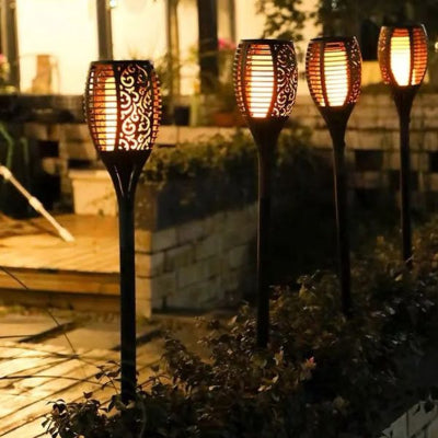 Lampe solaire extérieur torche LED effet flamme installée près d’une terrasse en soirée.