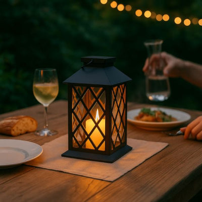lanterne au crépusculée posét sur une table à l'extéieur avec une personne en train de dîner