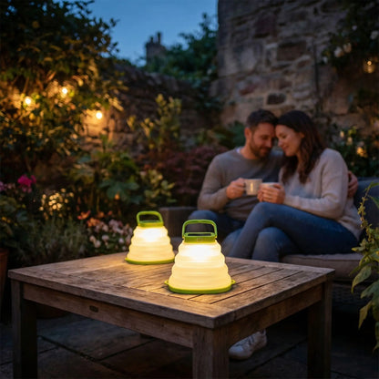 lanterne exterieur sur table basse en bois dans un jardin avec un couple avec des meugs sur un salon de jardin 