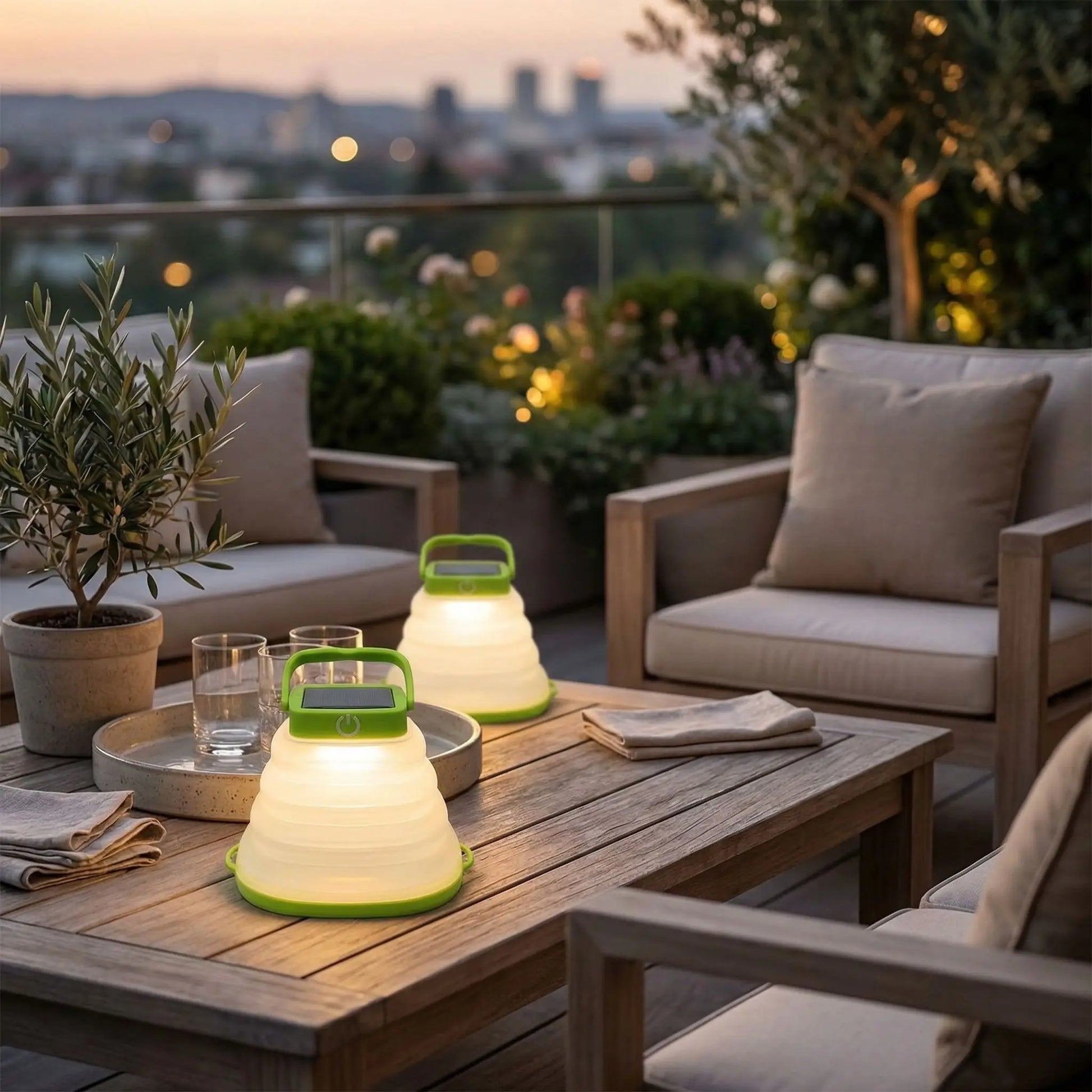 lanterne exterieur sur table basse avec plateau et deux verres, un olivier en pot et un salon de jardin sur terrasse floutée en arrière plan