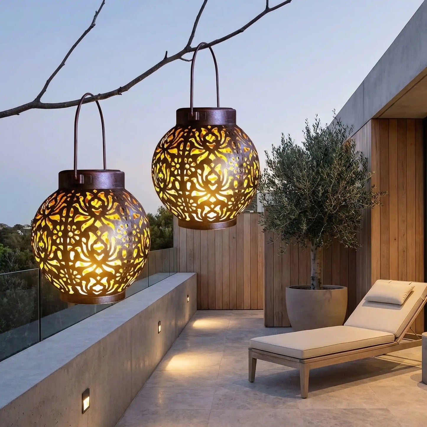 lanterne exterieur solaire accroché à une branche sur terrasse avec chaise longue et olivier dans un grand pot de fleur