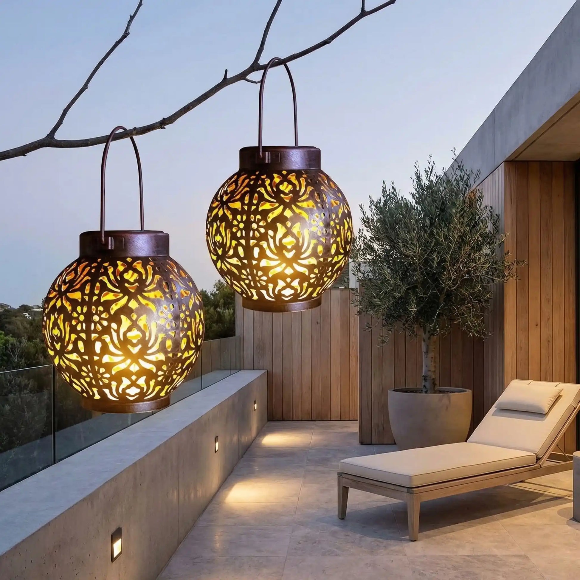 lanterne exterieur solaire accroché à une branche sur terrasse avec chaise longue et olivier dans un grand pot de fleur