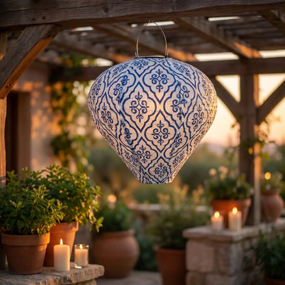 Lanterne solaire jardin bleu motifs arabesques suspendue sous une pergola en bois au coucher du soleil ambiance méditerranéenne