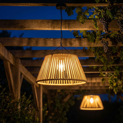 lustre solaire extérieur en rotin suspendu sous pergola en bois, lumière chaude dorée, ciel bleu nuit