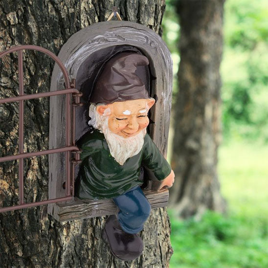 Nain de jardin rigolo sortant d'une fenêtre en bois accrochée à un arbre
