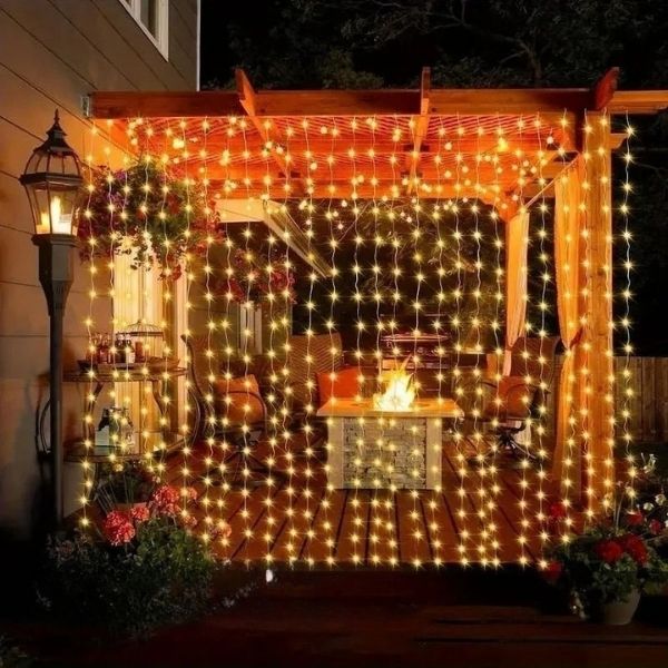 rideau lumineux blanc chaud sur tonnelle avec lampadaire accolé à une maison