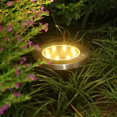 spot extérieur solaire LED blanc chaud éclairant un massif de fleurs