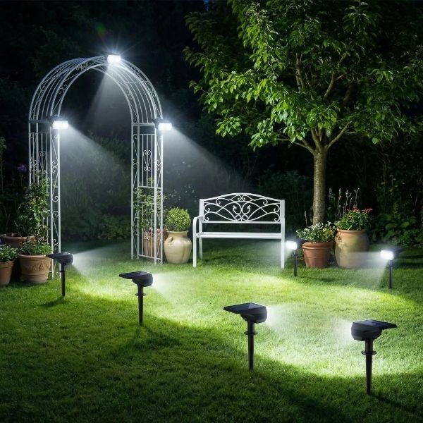 Plusieurs spot exterieur solaires blanc froid éclairant allée de jardin avec arche et banc blanc