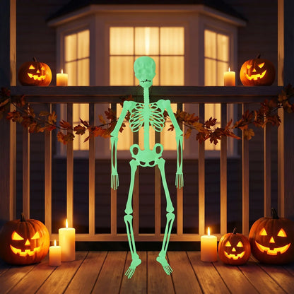 Squelette halloween lumineux vert suspendu à la rambarde d'une terrasse, entouré de citrouilles sculptées et de bougies allumées.
