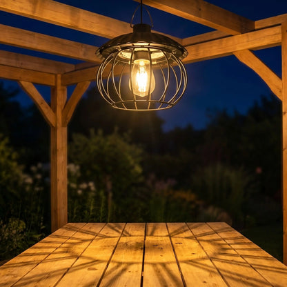 suspension exterieure suspendue a une pergola éclairant une table dans un jardin à la tombée de la nuit